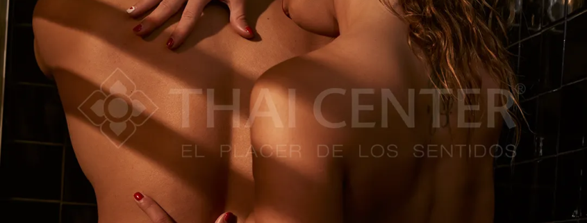 Masajista erótica deslizándose sobre el cuerpo de un hombre en masaje nuru con gel.